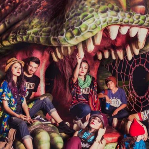 Jóvenes junto a dinosaurio de decoración